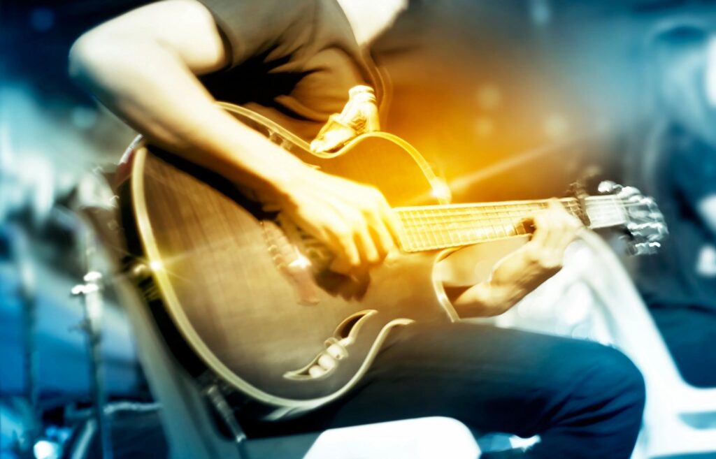 A person playing an electric guitar with warm lighting effects.